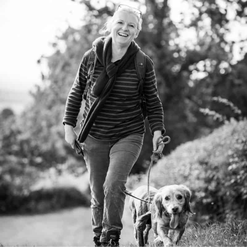 Comfortable woman walking dog outdoors in casual clothing, enjoying nature.
