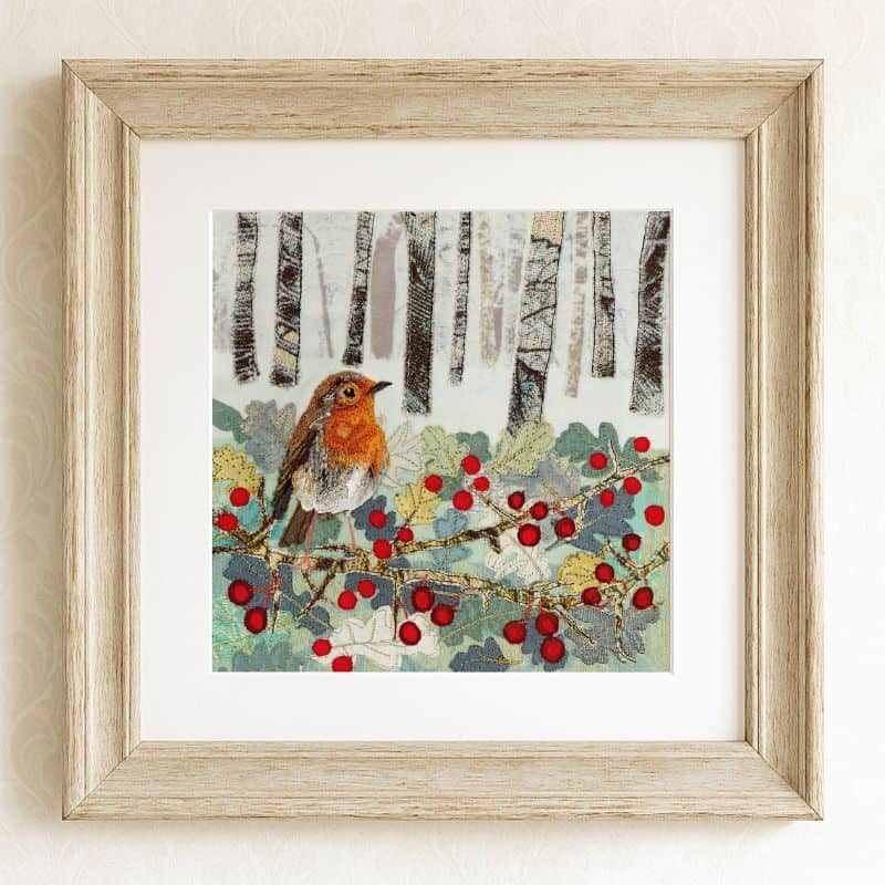 Colorful embroidered winter scene with robin and holly on white frame.